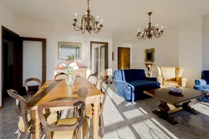 Un coin repas avec une table et des chaises en bois, un canapé bleu et un fauteuil à motifs.
