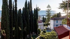 A coastal view with tall cypress trees, a marina, and buildings with red roofs. - GuestHost - Cozy penthouse of 110 sqm, able to accommodate up to 4 people, located on the fourth floor of a building with elevator and private garage.The apartment boasts an enchanting view of the sea and Portosole, surrounded by Villa Ormond's and Villa (Sanremo)