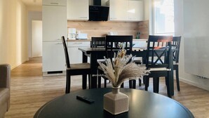 Une cuisine moderne avec des meubles blancs, un plan de travail en bois et un coin repas comprenant une table ronde et des chaises.