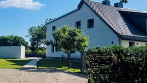 Une maison moderne à deux étages, dotée d’un toit en pente, d  ’un petit porche à l’avant et d’une pelouse bien entretenue.