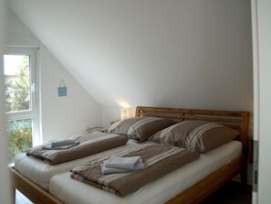 A single bed with a wooden headboard in a room with sloped ceilings. - Ferienhaus auf der Insel Poel mit Sauna (Insel Poel)