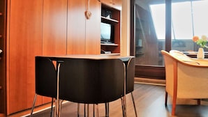 A modern kitchen with wooden cabinets, a black dining table with chairs, and a television on a shelf. - Ferienwohnung in Winterberg am Skigebiet (Winterberg)