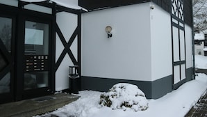 A building with a black and white exterior, a visible entrance, and a snow-covered ground. - Ferienwohnung in Winterberg am Skigebiet (Winterberg)