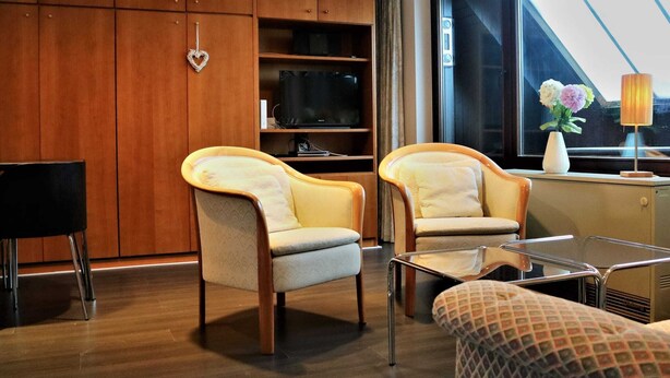 A modern living room with two armchairs, a small table, a TV, and a large window with a view. - Ferienwohnung in Winterberg am Skigebiet (Winterberg)
