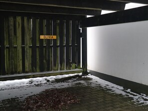 Ein hölzernes Tor mit einem Schild mit der Aufschrift 'OLIVIA' und einem schneebedeckten Boden mit herabgefallenen Blättern.
