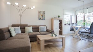 A modern living room with a sectional sofa, a wooden coffee table, a dining area with a table and chairs, and a cabinet with shelves. - Kleine Wohnung Nahe von Winterbergs Skikarussell (Winterberg)