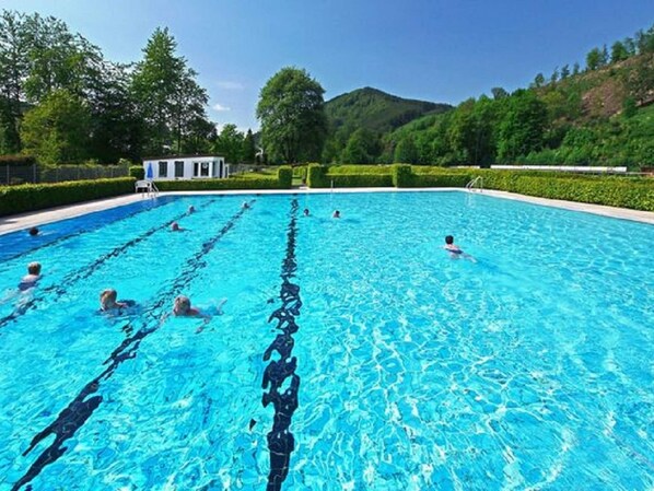 Relax by the serene pool surrounded by lush greenery and a scenic hilly landscape.