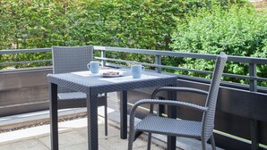 An outdoor patio with wicker furniture, including a table and two chairs, a white mug, and a plate with food. - Kleine Wohnung Nahe von Winterbergs Skikarussell (Winterberg)