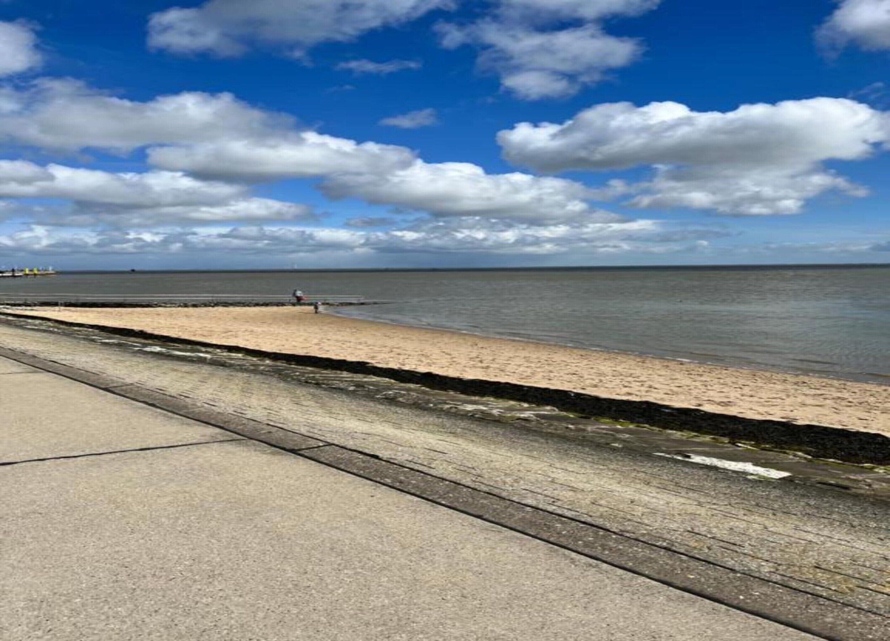Un paseo marítimo con una playa de arena y un camino de hormigón.