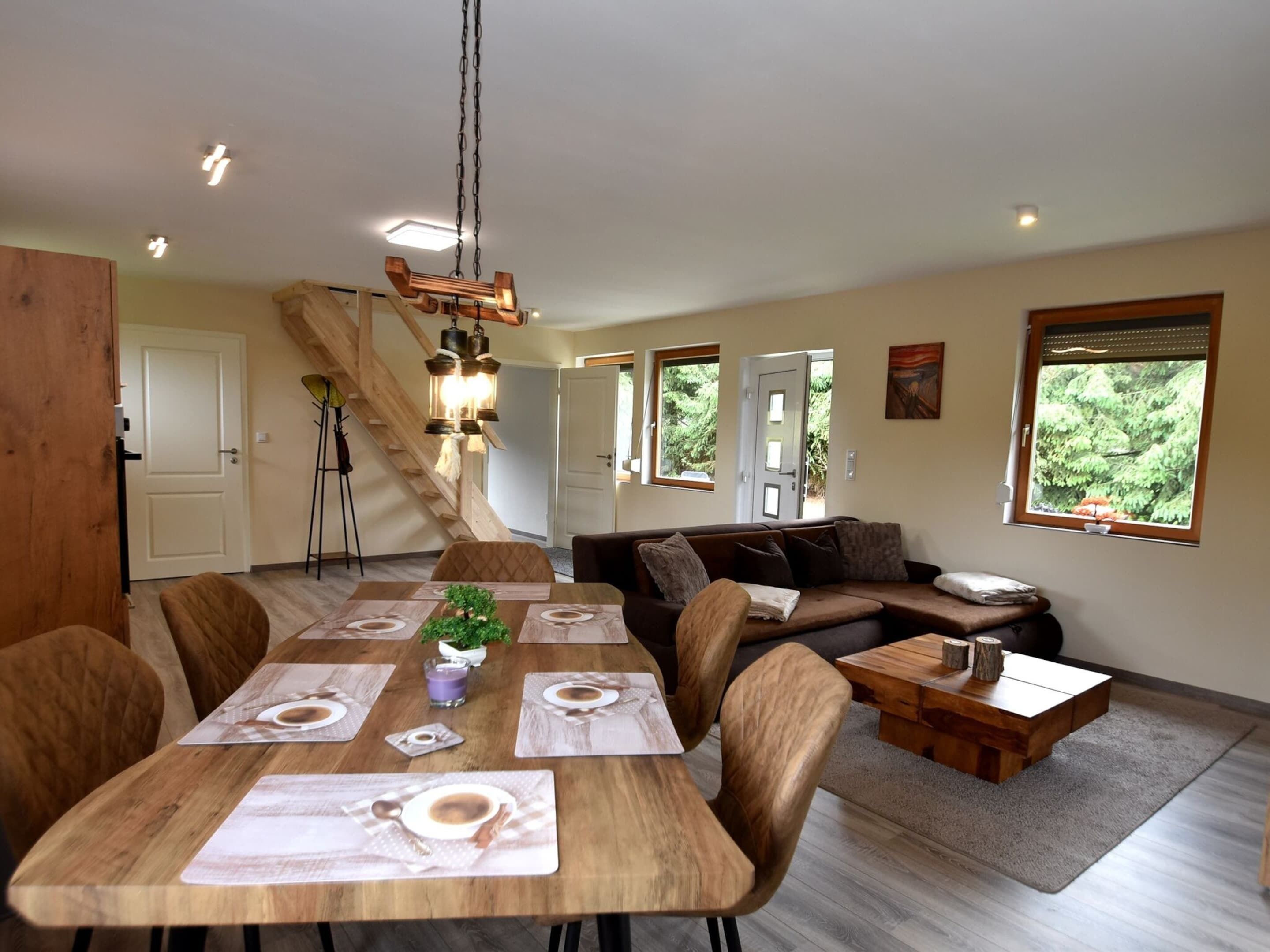 A dining area with a wooden table set for four, a sofa, and a small wooden side table.