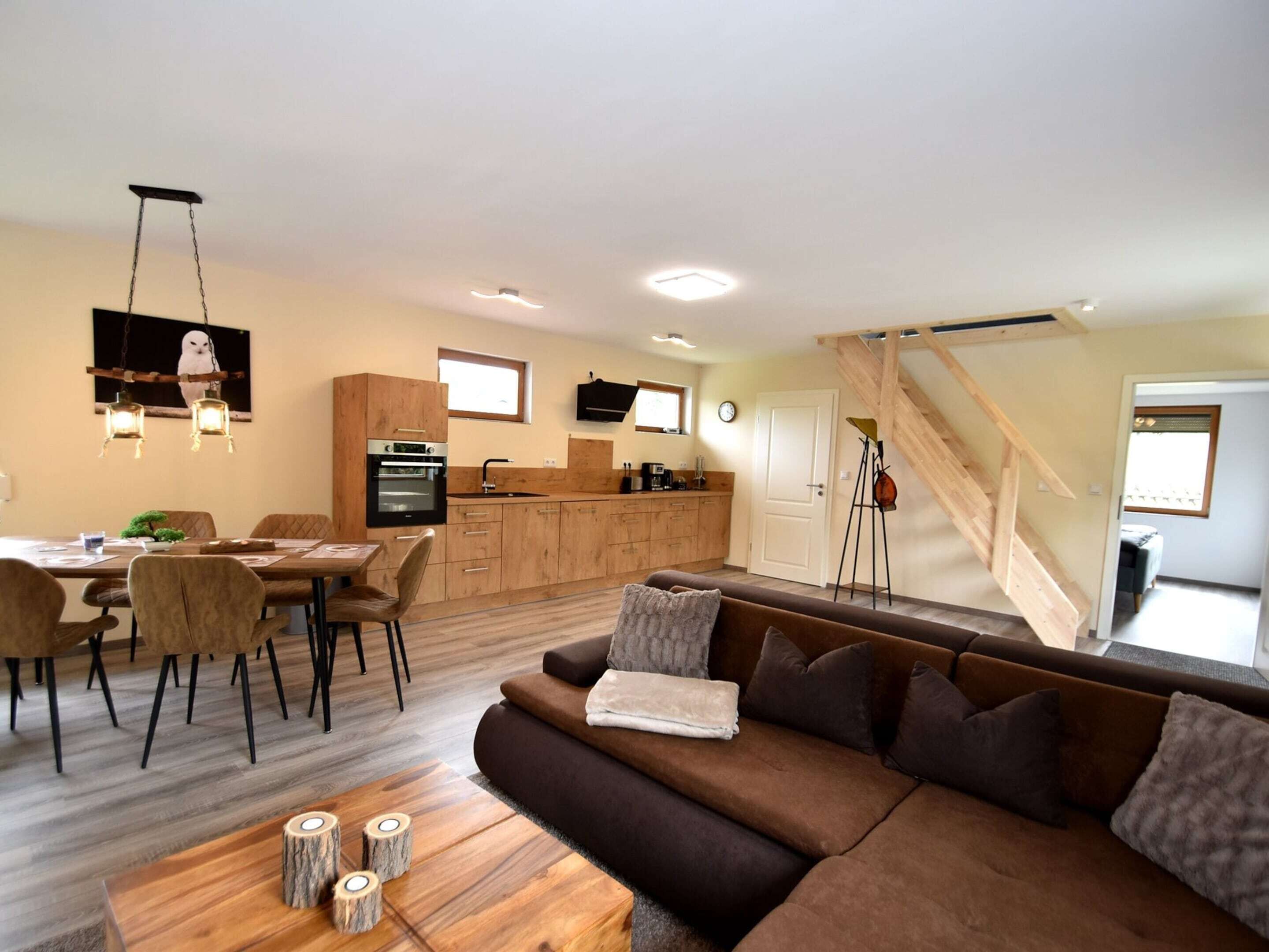 Un espacio habitable moderno con cocina, comedor y escalera.