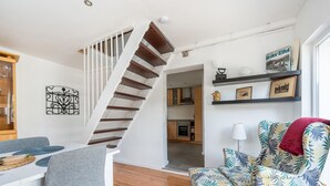 A modern living room with a wooden staircase, a dining area, and a kitchen in the background. - Pretty Holiday Home in Schleiden With Balcony and Barbecue (Schleiden)
