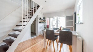 A modern interior with a staircase, wooden flooring, a dining area with chairs and a table, and a radiator. - Pretty Holiday Home in Schleiden With Balcony and Barbecue (Schleiden)