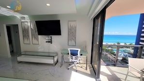 Et moderne hotelværelse med balkon, fladskærms-TV, skrivebord i glas og kunst på væggene.