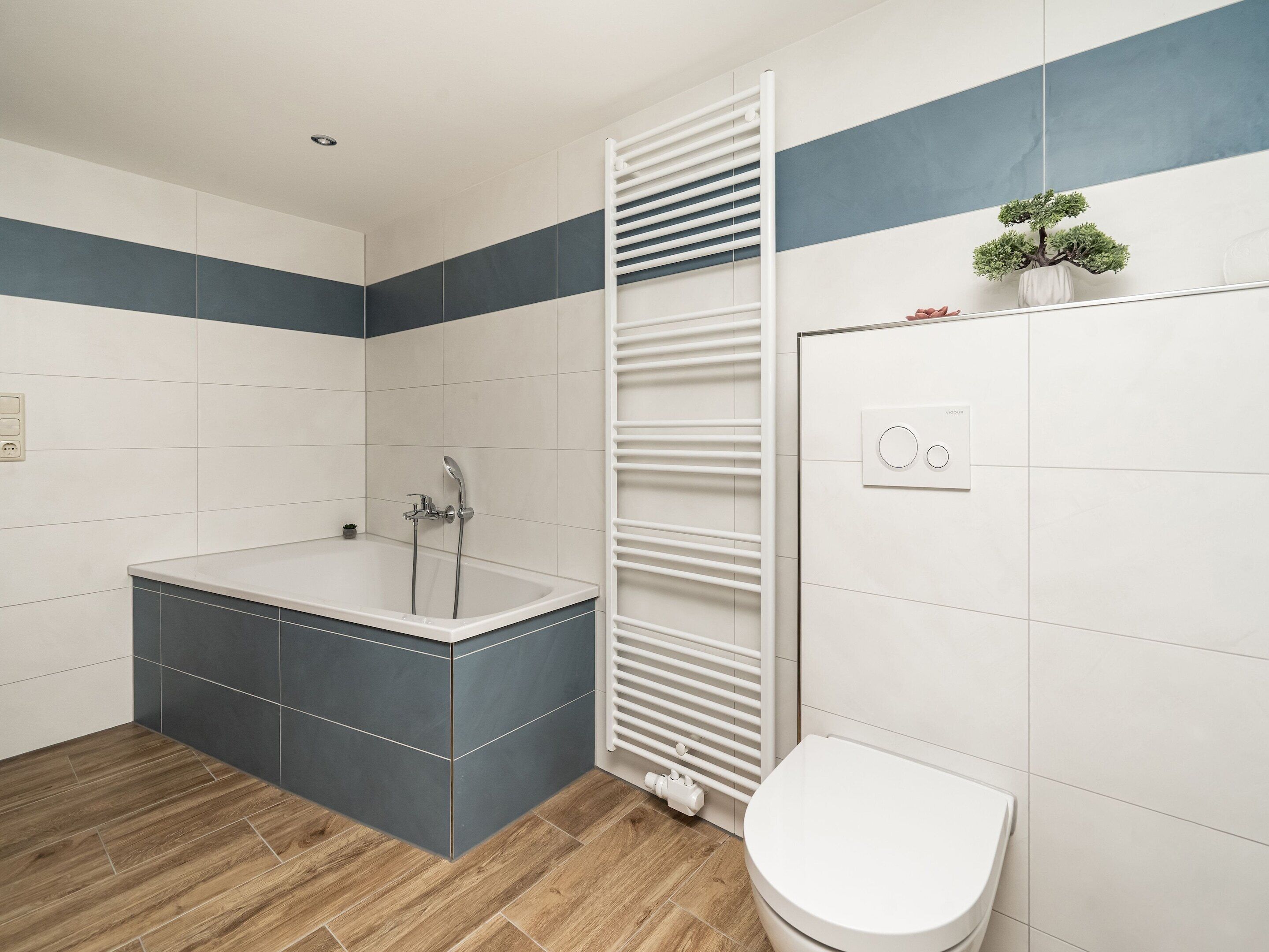 Un baño moderno con bañera, inodoro y un perchero para toallas.