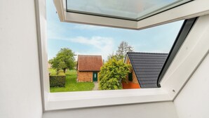 Ein Dachfenster mit Blick auf ein Wohngebiet, mit einem Ziegelhaus und einer grünen Tür.