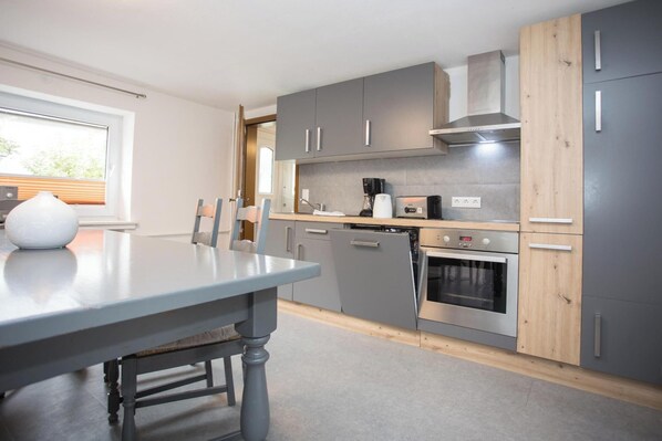 A modern kitchen with grey cabinets, a wooden countertop, a built-in oven, and a coffee maker. - Geraumige Wohnung Direkt am Skigebiet Gelegen (Winterberg)