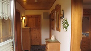 A hallway with wooden doors, a small wooden cabinet, and a mirror on the wall. - Apartment in Langewiese Near Winterberg (Winterberg)
