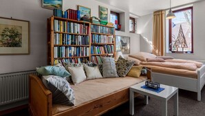 A cozy living room with a wooden sofa, a bookshelf, a small table, and a window with curtains. - Flat in Meldorf Next to the Town Centre (Meldorf)