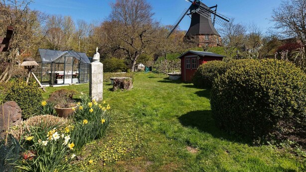A windmill, a greenhouse, and a red building in a garden setting. - Flat in Meldorf Next to the Town Centre (Meldorf)