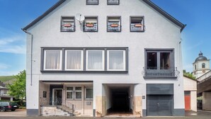 A two-story building with a gabled roof, multiple windows, and a garage door. - Apartment in Kinheim With Lots of Space (Kinheim)