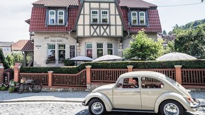 En traditionell byggnad med ett café och en trädgårdsbar, en veteranbil parkerad framför och en kullerstensgata.