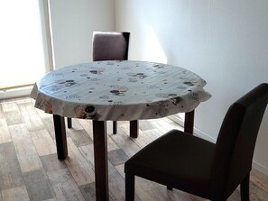 A round dining table with a tablecloth featuring coffee and cookie prints, surrounded by dark chairs. - Ferienwohnung im Idyllischen Ziesar (Ziesar)