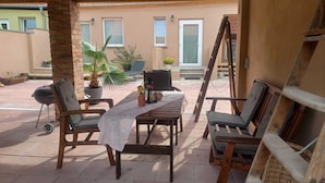 An outdoor patio area with a wooden table and chairs, a grill, and potted plants. - Ferienwohnung im Idyllischen Ziesar (Ziesar)