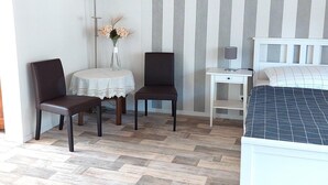A bedroom with a bed, two chairs, a small table with a vase, and a bedside table with a lamp. - Ferienwohnung im Idyllischen Ziesar (Ziesar)