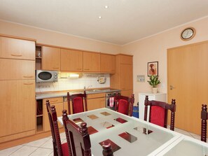 Une cuisine compacte dotée de meubles en bois, d’un four à micro-ondes, d’une cuisinière et d’une table à manger avec des chaises.