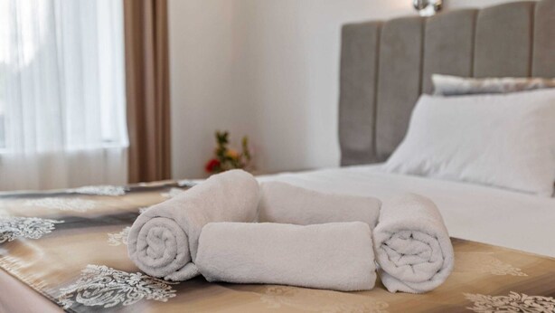 A neatly made bed with white linens and a decorative headboard. - Apartment in Oberhausen Near Dusseldorf (Oberhausen)