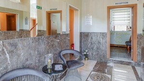 A reception area with marble flooring, a reception desk, and two chairs. - Apartment in Oberhausen Near Dusseldorf (Oberhausen)