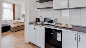 A modern kitchen with white cabinets, a microwave, a sink, and a dishwasher. - Apartment in Oberhausen Near Dusseldorf (Oberhausen)