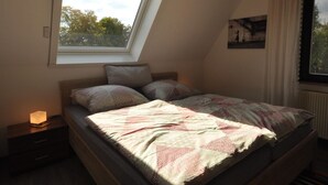 A bedroom with a sloped ceiling, a skylight, a bed with patterned bedding, a bedside table with a lamp, and a framed picture on the wall. - Wohnung in Frankenberg fur Radfahrer (Frankenberg)