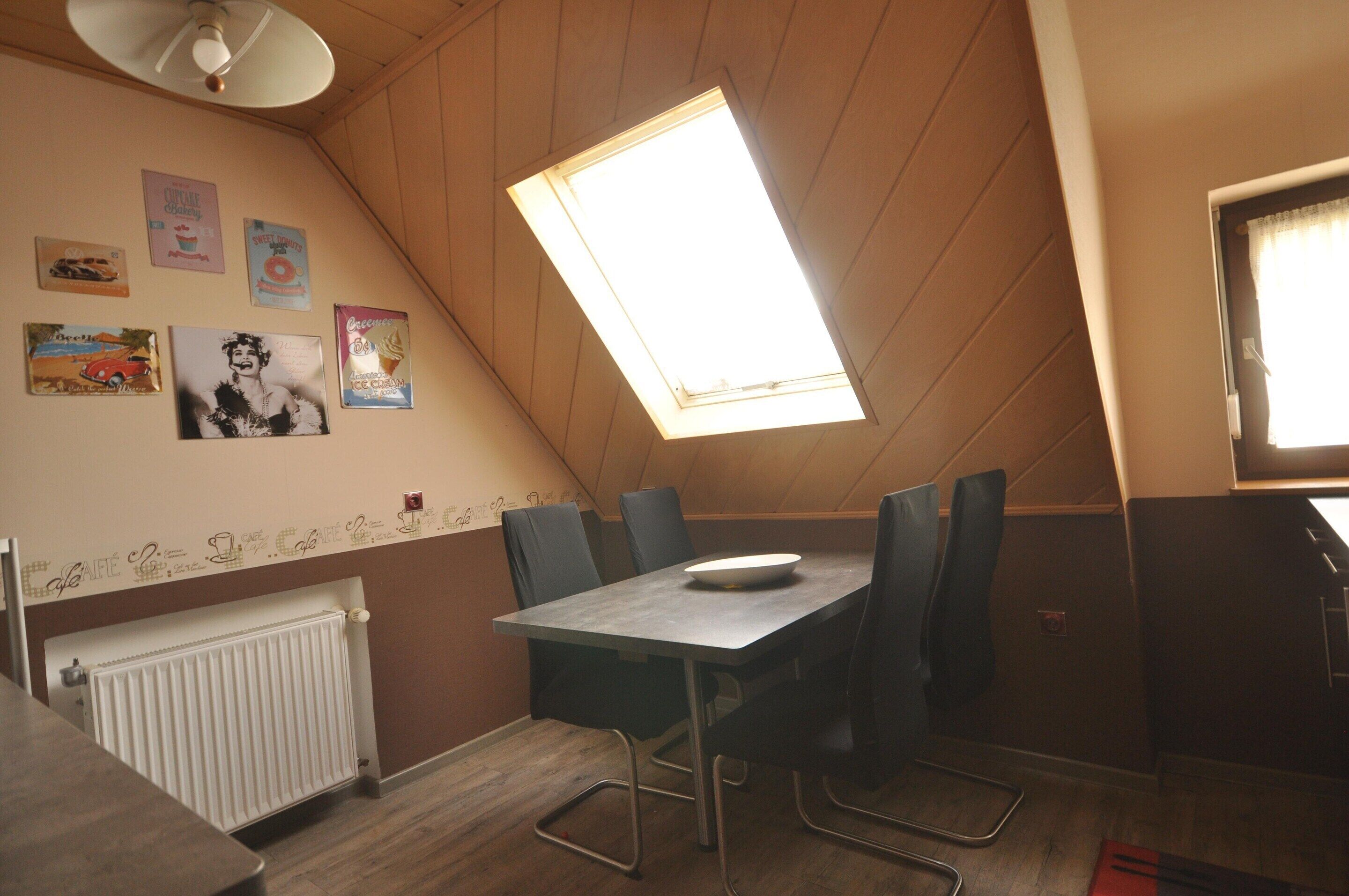 Un comedor con una mesa, sillas, un radiador y adornos en la pared.