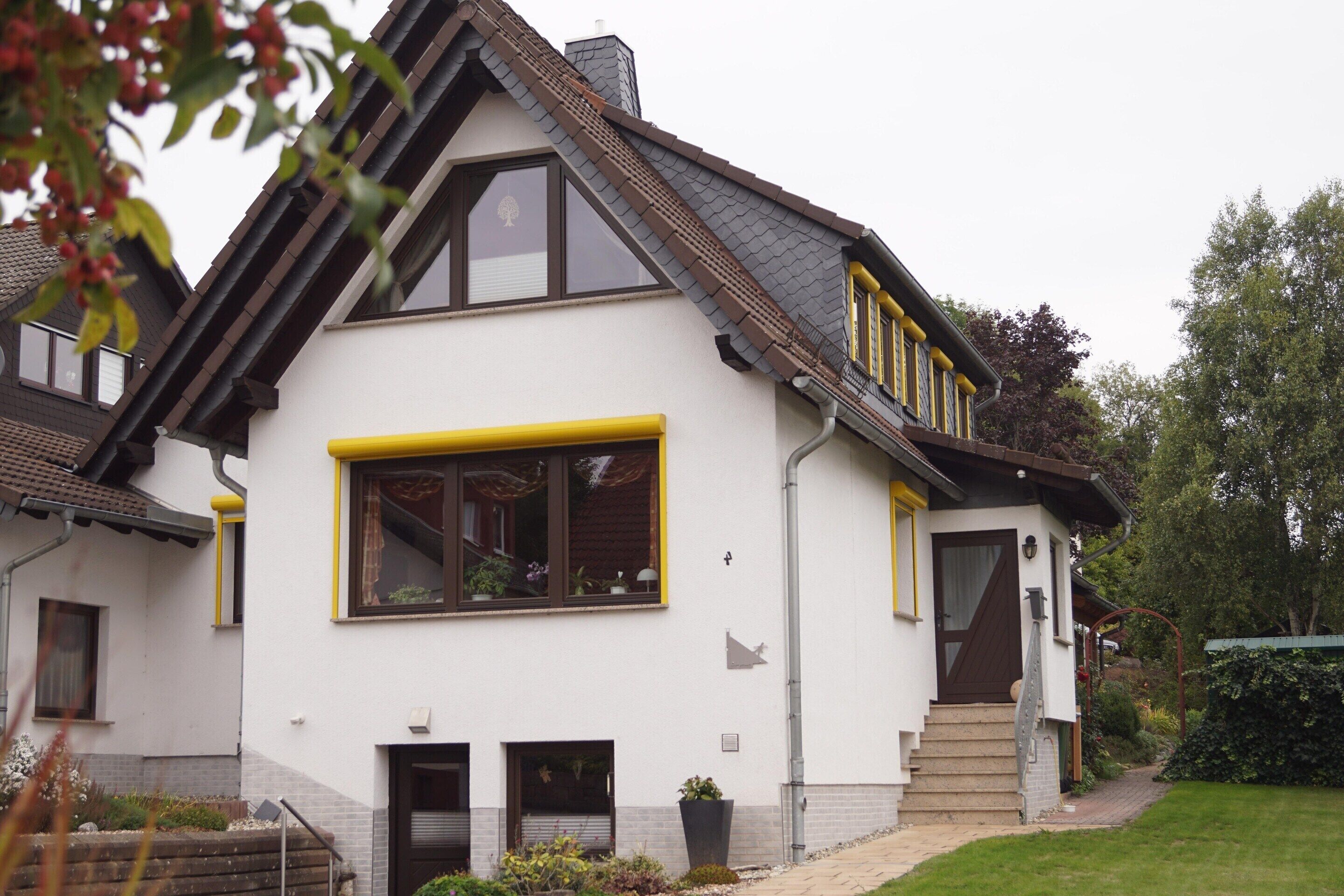Une maison à deux étages, dotée d’un toit à forte pente, de grandes fenêtres et d’un petit porche à l’avant.