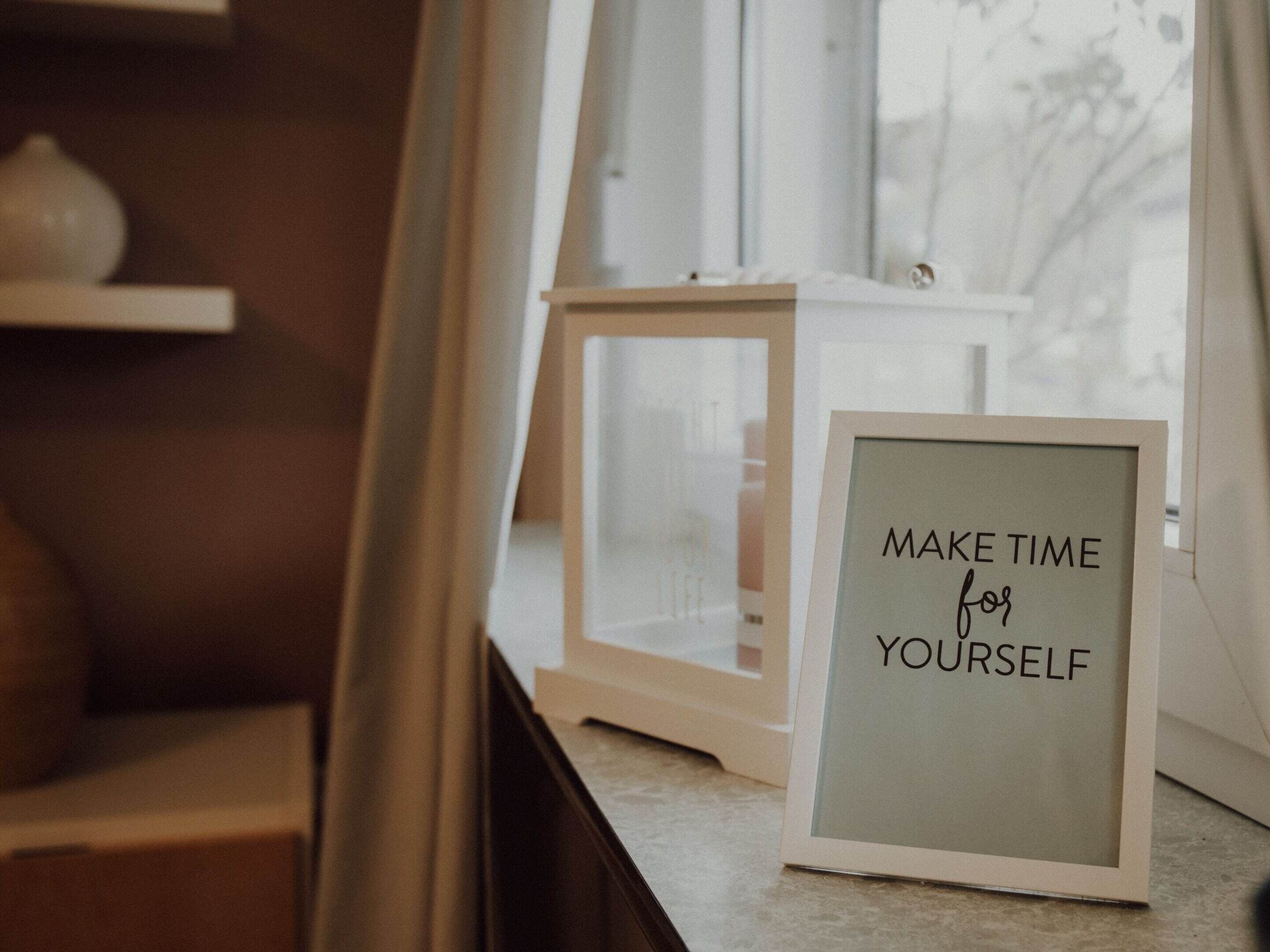 A framed sign with the text "MAKE TIME for YOURSELF" on a table.