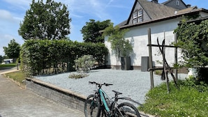 A residential area with a house, a gravel driveway, and a parked bicycle. - Modernes Appartement Neben Einem Skigebiet (Winterberg)