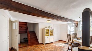 A spacious room with a tiled floor, a wooden staircase, a white cabinet, and a black heater. - Romantic Holiday Home in Schleiden on the Village Square (Schleiden)
