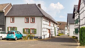 A traditional European street with half-timbered houses, a paved road, and parked cars. - Romantic Holiday Home in Schleiden on the Village Square (Schleiden)