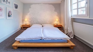 A bedroom with a bed, two bedside lamps, a window, and a radiator. - Romantic Holiday Home in Schleiden on the Village Square (Schleiden)