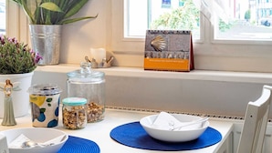 A breakfast table with a calendar, jars of granola, a plant, and a window with a view of buildings. - Romantic Holiday Home in Schleiden on the Village Square (Schleiden)