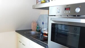 Eine moderne Küche mit Backofen aus Edelstahl, einer digitalen Uhr und einem Spülbecken.