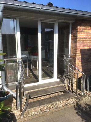Ein Wohngebäude mit einer Veranda, einem Metallgeländer und einer kleinen Sitzgelegenheit im Freien.
