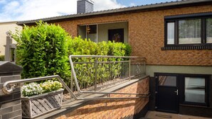 A modern building with a brick facade, a metal railing, and a black door. - Snug Apartment in Grevesmuhlen With Terrace (Grevesmuehlen)