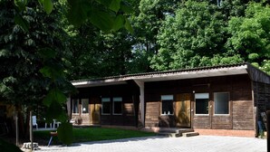 A rustic wooden building with a tiled entrance, surrounded by lush greenery. - Bungalow in the Harz Mountains With Terrace (Oberharz am Brocken)
