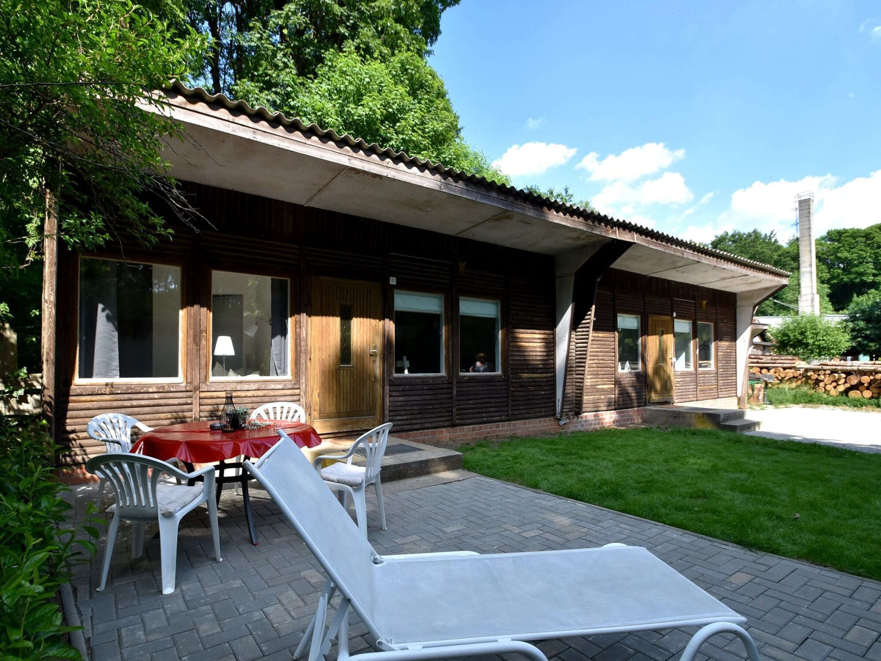 Eine Holzhütte mit einer Terrasse, inklusive Tisch und Stühlen, sowie einem überdachten Sitzbereich im Freien.