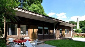 A wooden cabin with a patio area, including a table and chairs, and a covered outdoor seating area. - Bungalow in the Harz Mountains With Terrace (Oberharz am Brocken)