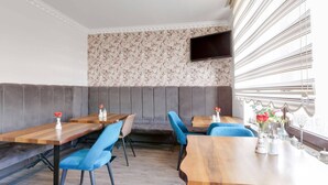 A restaurant with wooden tables and blue chairs, a floral wall, and a TV mounted on the wall. - Apartment in Oberhausen Near Ski Resort (Oberhausen)