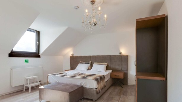 A bedroom with a sloped ceiling, a bed with a headboard, a nightstand, a small table, and a wardrobe. - Apartment in Oberhausen Near Ski Resort (Oberhausen)